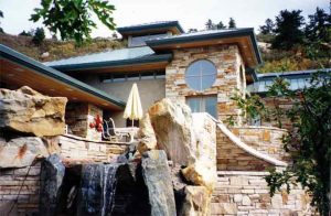 Exterior of beautiful home showing Water Fall, outdoor soffit speakers installed and Touchpanel control for Audio, Video, and Control Systems